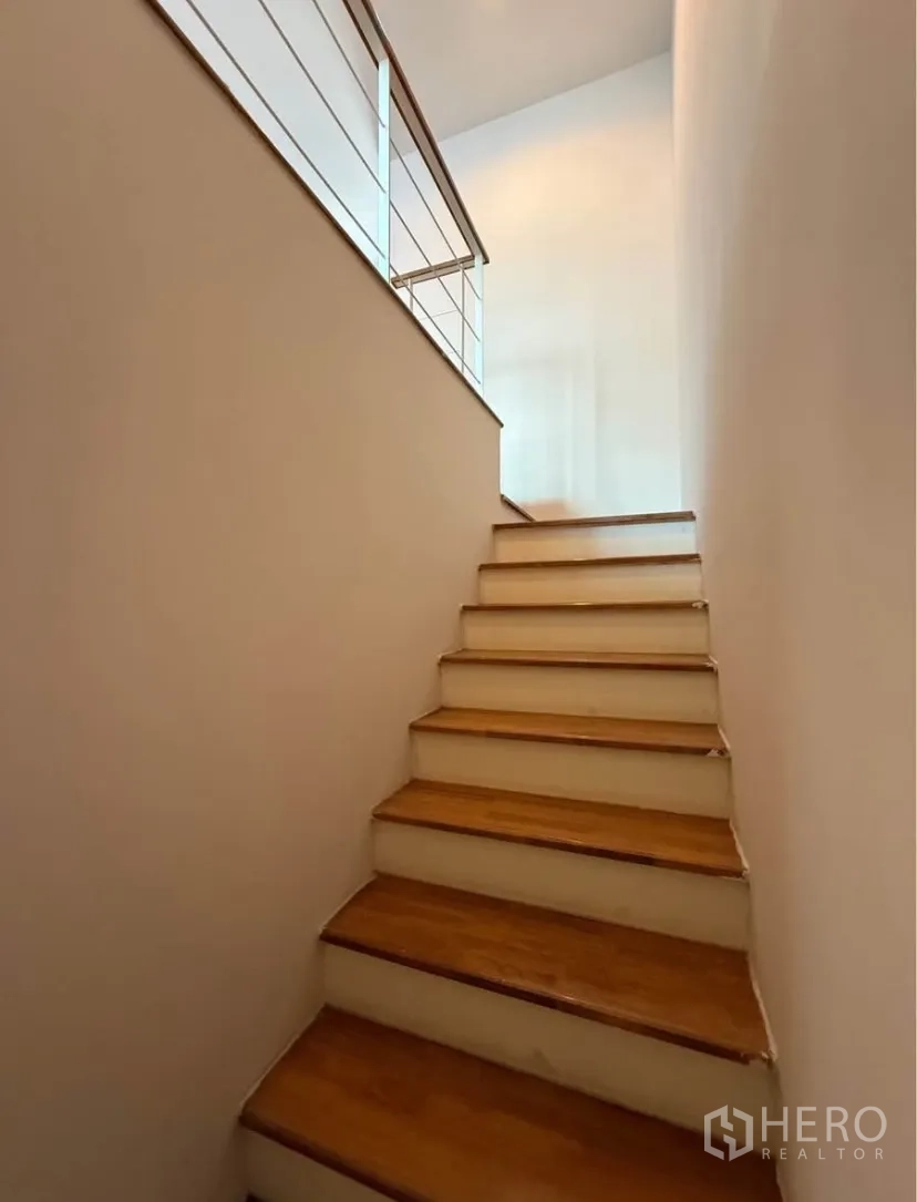 Townhouse for rent in Suan Luang, Bangkok - Staircase with wooden steps and metal handrail to upper level.