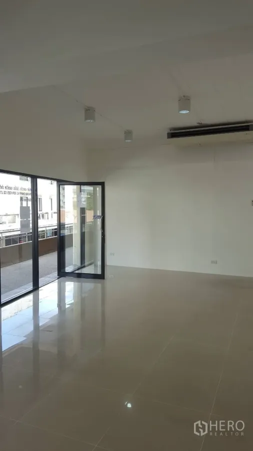 办公空间 出租在Khlong Toei, Bangkok - 明亮的开放式办公空间，亮面地砖、白色墙面、射灯与通往阳台的落地推拉门（Phra Khanong）。