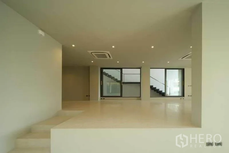 Home Office for sale in Wang Thonglang, Bangkok - Large open workspace with ceiling AC units and floor-to-ceiling windows by the stairs.