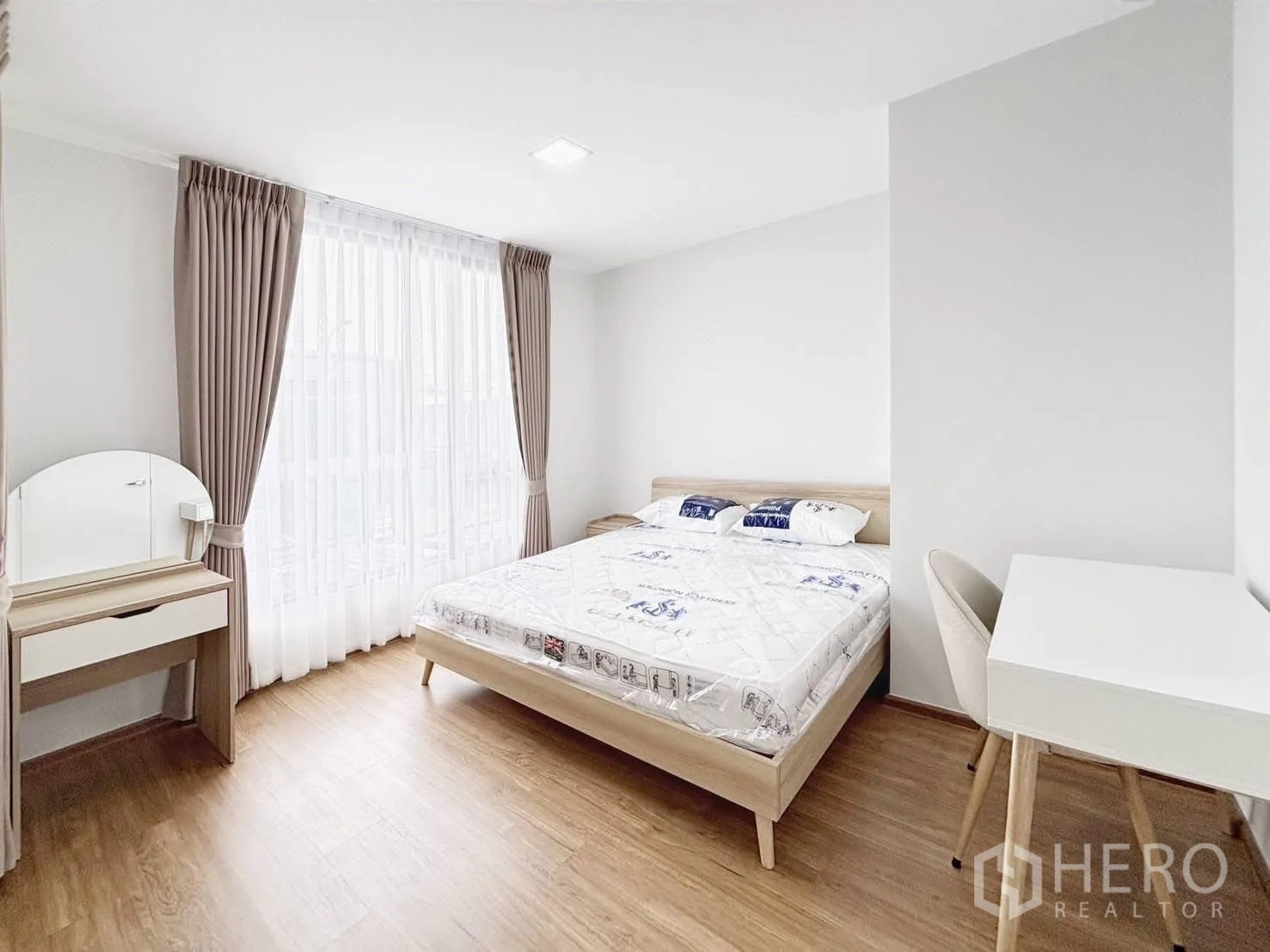Townhouse for rent in Bang Phli, Samut Prakan - Large master bedroom with double bed, vanity, desk, and full-height windows with curtains.