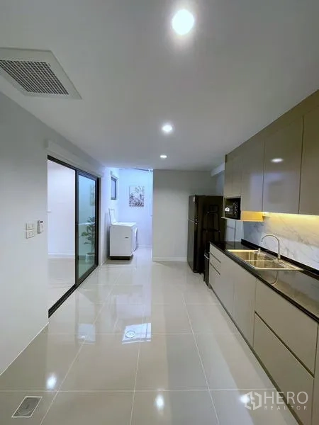 联排别墅 出租在Bang Phli, Samut Prakan - 一字型厨房，长台面、亮面橱柜与冰箱。