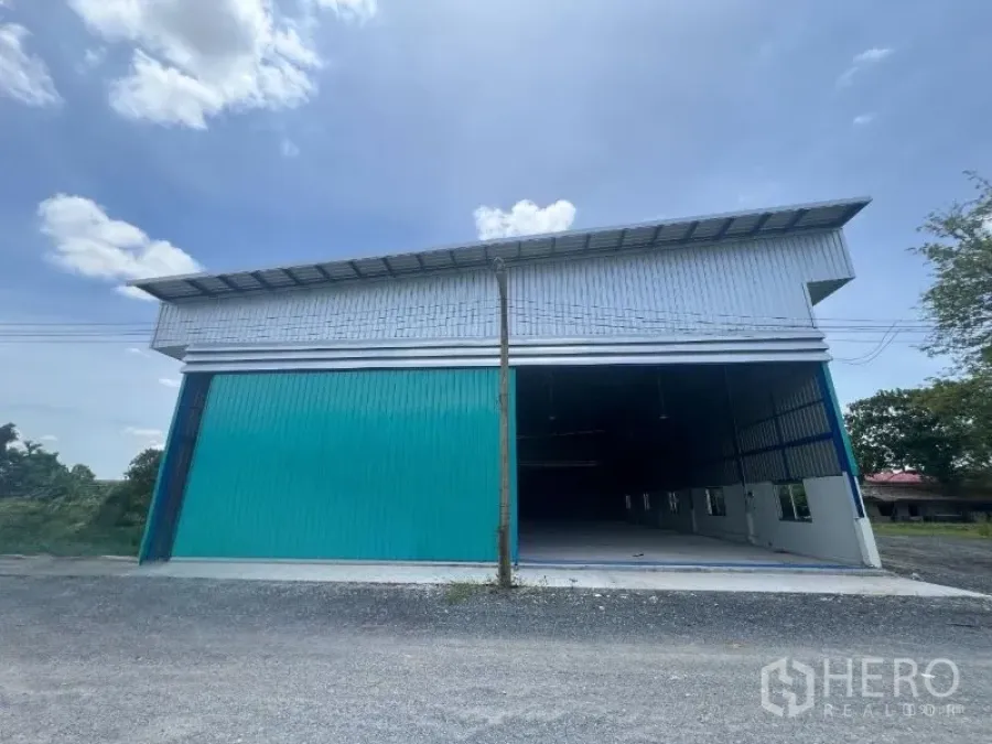 货栈 出租在Min Buri, Bangkok - 仓库正面，青绿色推拉大门与高屋顶，临碎石道路，位于曼谷敏武里。