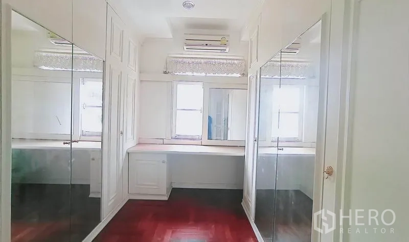Detached House for sale in Bang Kapi, Bangkok - Walk-in closet with mirrored wardrobes, white cabinetry and a dressing table.