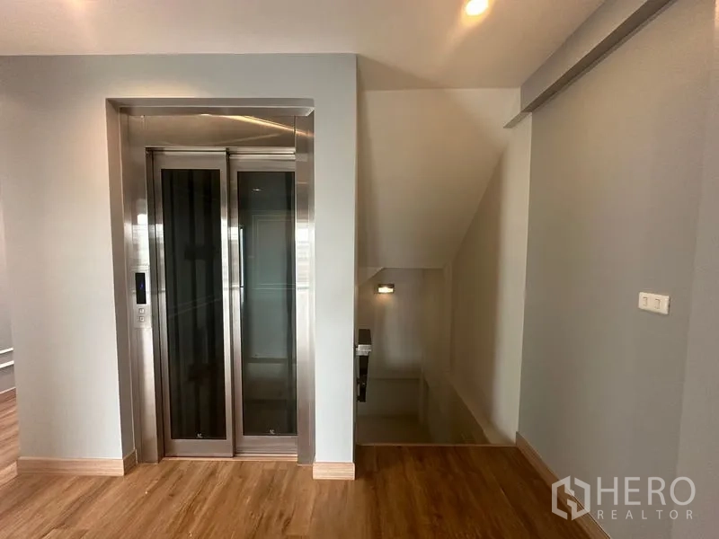 Home Office for rent in Suan Luang, Bangkok - Corner room with sliding balcony door, curtains, and wood floor.