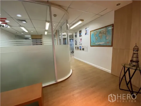 Office Space for rent in Khlong Toei, Bangkok - Hallway with curved frosted glass meeting room partitions, wood floors and wall displays.