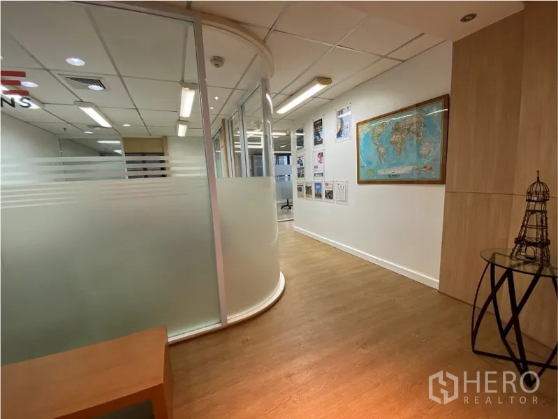 Office Space for rent in Khlong Toei, Bangkok - Hallway with curved frosted glass meeting room partitions, wood floors and wall displays.