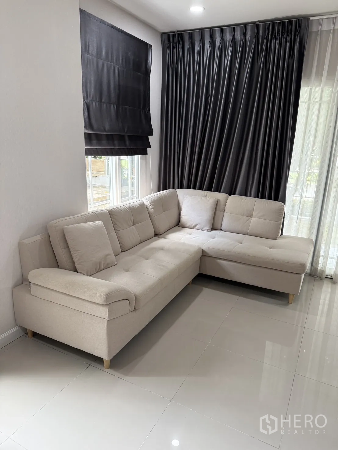 Detached House for rent in Bang Kapi, Bangkok - Cozy living space with an L-shaped beige sofa and floor-to-ceiling curtains.