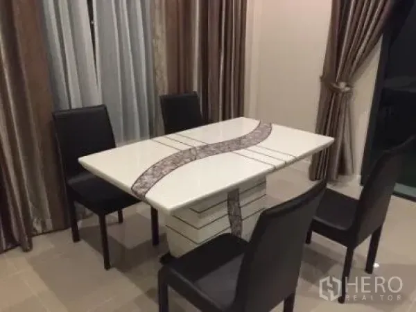 Detached House for rent in Bang Kapi, Bangkok - Dining corner with white table and four black chairs beside full-length curtains.