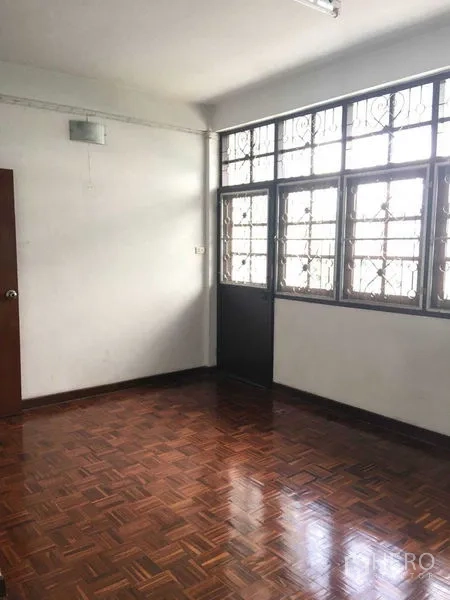 Townhouse for rent in Phra Khanong, Bangkok - Bright bedroom with parquet flooring and large windows with security grilles.