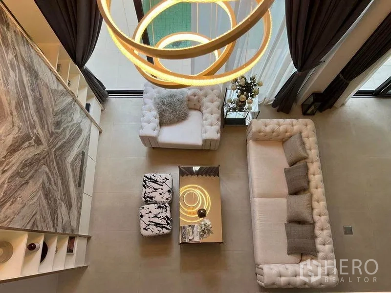 Detached House for sale in Suan Luang, Bangkok - Aerial view of a double-height living room with tufted sofas, marble feature wall and modern lighting.