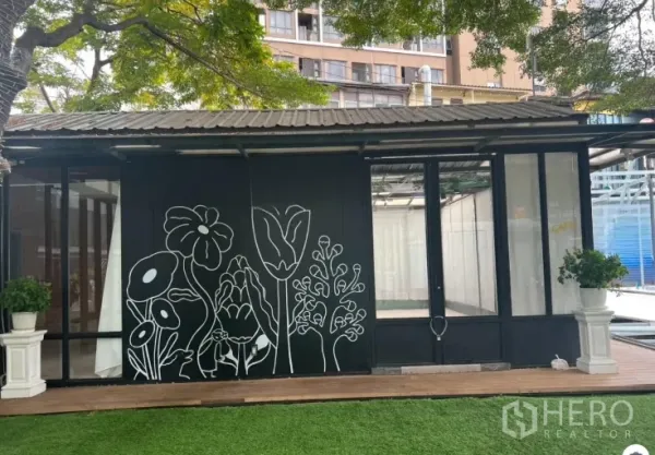 Retail Space for rent in Watthana, Bangkok - Street-facing glass storefront with black floral mural, planters and lawn, ideal for a café or boutique.