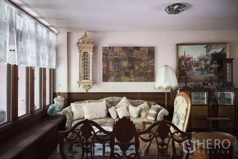 Townhouse for rent in Khlong Toei, Bangkok - Cozy lounge with lace curtains, classic sofa and framed artwork