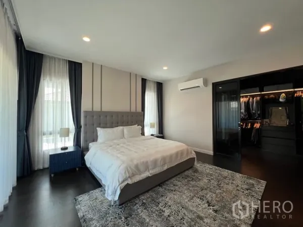 Detached House for rent in Bang Kapi, Bangkok - Master bedroom view toward the walk-in closet with glass door and wall-mounted air conditioner.