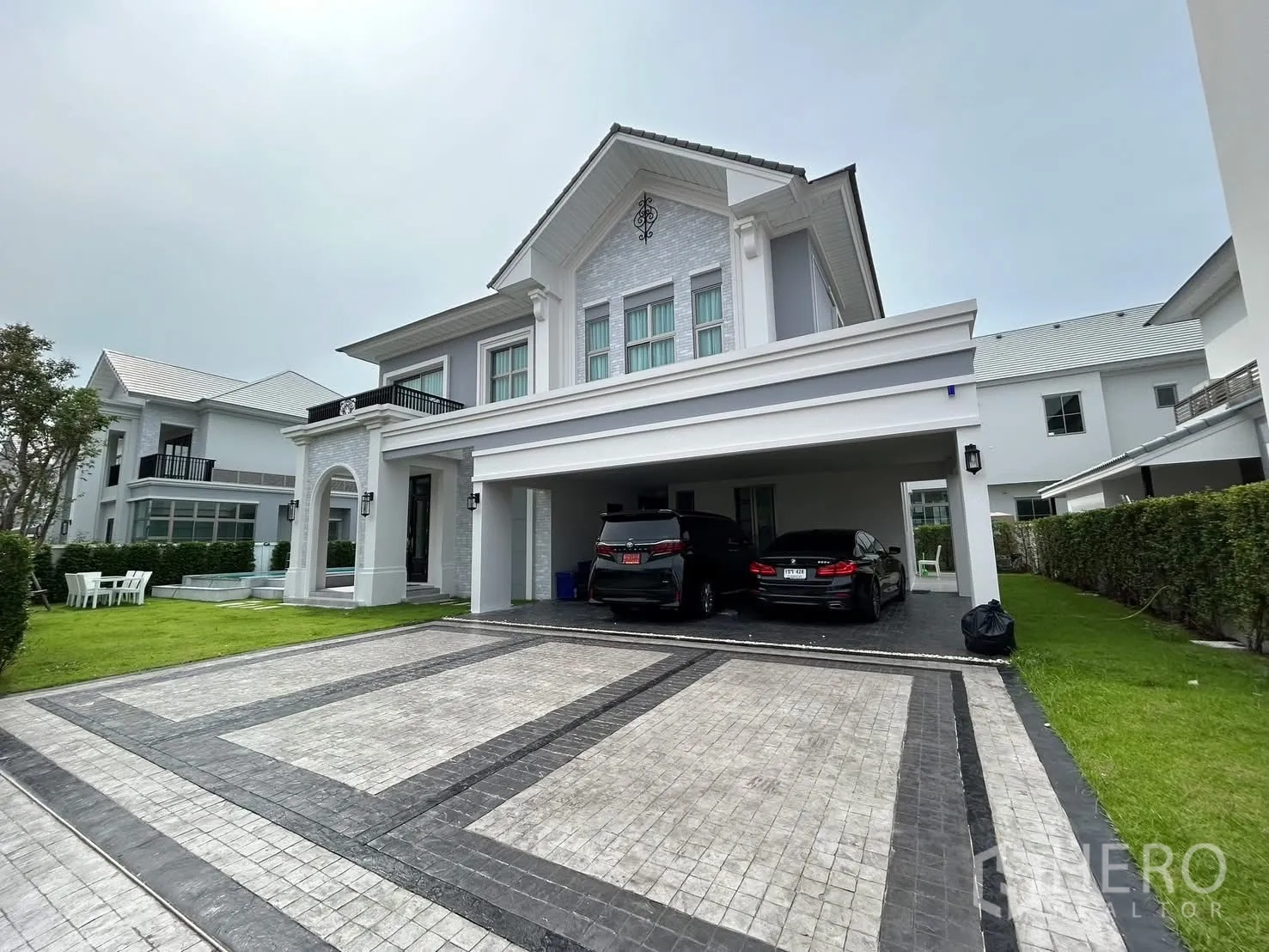 Detached House for rent or sale in Bang Phli, Samut Prakan - Elegant two-storey detached house facade with wide driveway, covered parking and lawn.