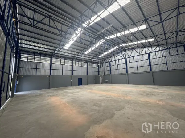 货栈 出租在Bang Phli, Samut Prakan - 宽敞仓库内部，高钢结构屋顶带采光板，混凝土地面与多扇出入口。