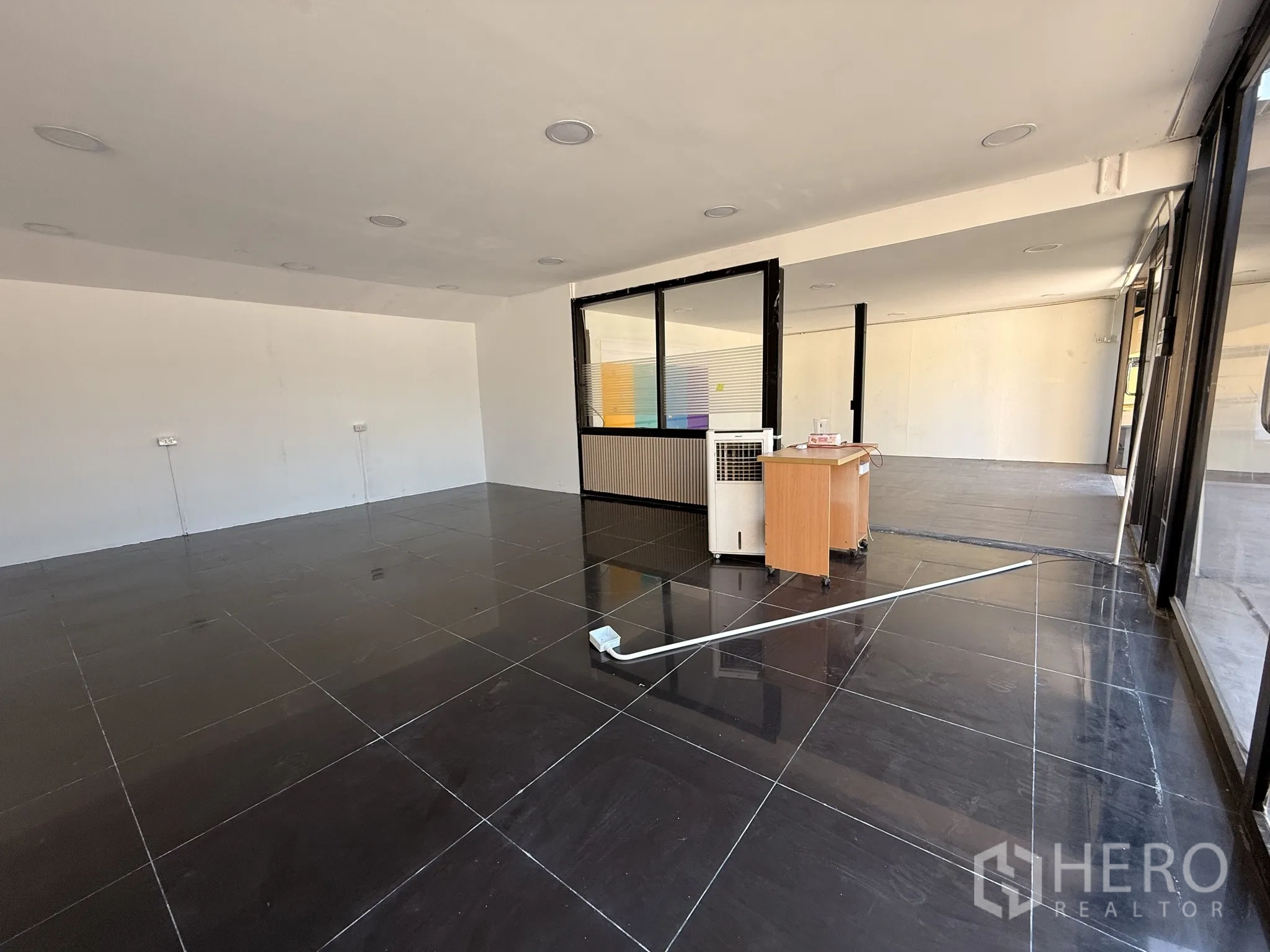 Warehouse for rent in Lat Krabang, Bangkok - Open-plan showroom or office area with black tiled floor, glass walls, and a small reception counter.