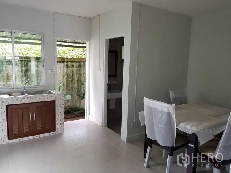 Townhouse for rent in Bang Kapi, Bangkok - Compact Thai kitchen with sink and window, opening to a small service yard beside dining area.