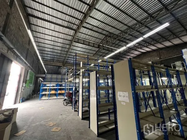Warehouse for rent in Khlong Toei, Bangkok - Spacious warehouse interior with high steel roof, LED lighting, and blue industrial shelving.