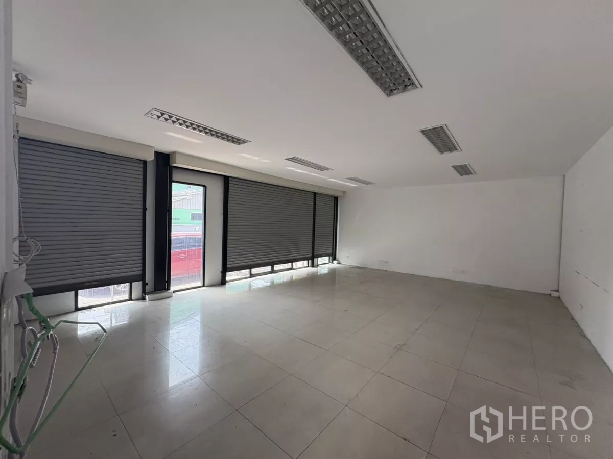 Warehouse for rent in Bang Phli, Samut Prakan - Bright front office with tiled flooring, roller shutters, and fluorescent lighting.