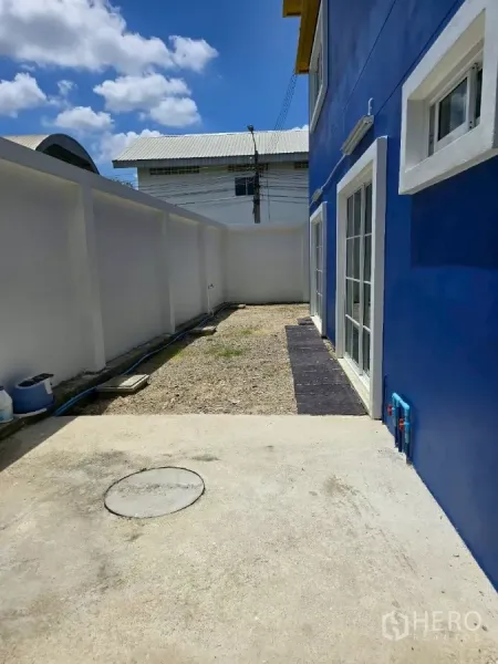 Warehouse for rent or sale in Khlong Toei, Bangkok - Private rear yard beside a white boundary wall and sliding glass doors.