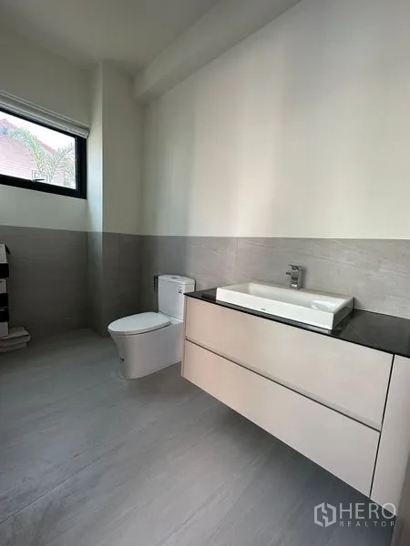 Detached House for rent in Watthana, Bangkok - Minimalist light-gray bathroom with window, wall-hung vanity, and toilet.