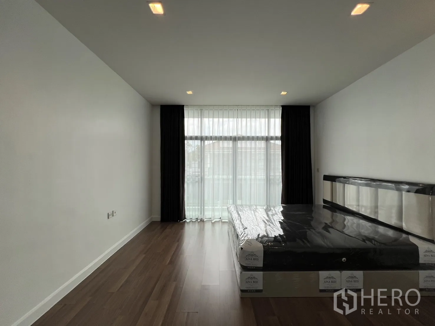 Detached House for rent in Bang Kapi, Bangkok - Spacious master bedroom with floor-to-ceiling curtains and soft lighting.