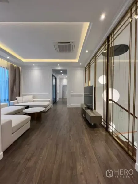 Detached House for rent in Phaya Thai, Bangkok - Elegant living room with wood floors, cove ceiling lights and TV area by the stair screen.