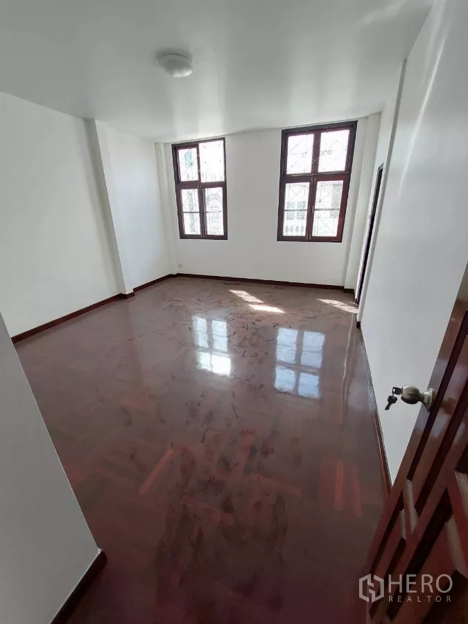 Home Office for rent in Yan Nawa, Bangkok - Corner office room with tall grid windows and glossy wooden floor.