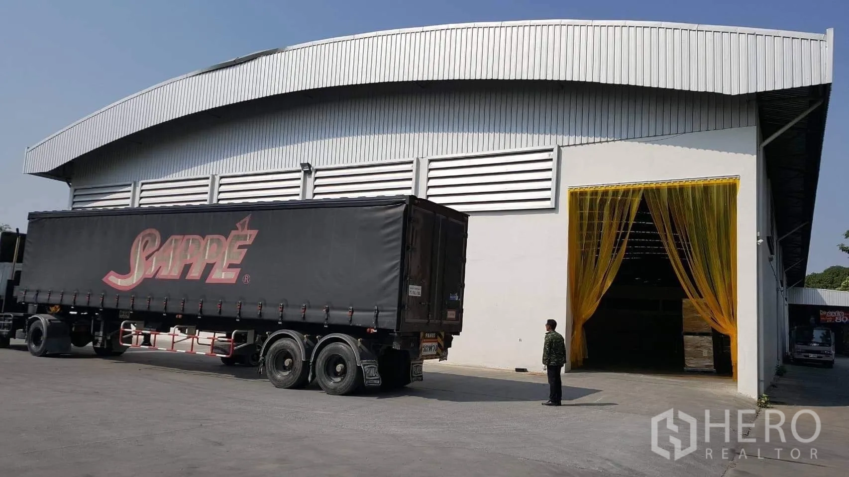Factory for rent or sale in Pathum Thani - Semi-trailer parked at the factory entrance with yellow PVC loading curtain.