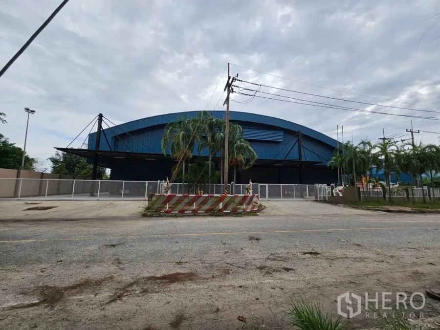 โรงงาน for rent in Si Racha, Chon Buri - มุมหน้าทางเข้าโรงงานหลังคาสีน้ำเงิน พร้อมรั้วล้อมรอบในศรีราชา