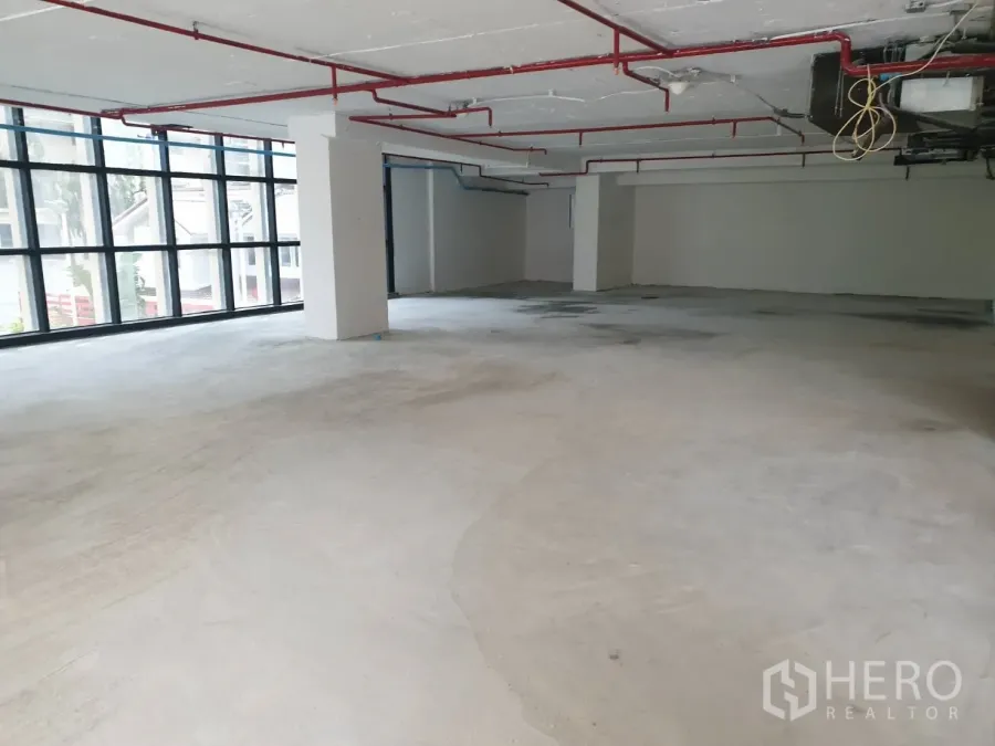 Retail Space for rent in Watthana, Bangkok - Open-plan retail floor with exposed ceiling, red sprinkler pipes, structural columns, and a large window wall.