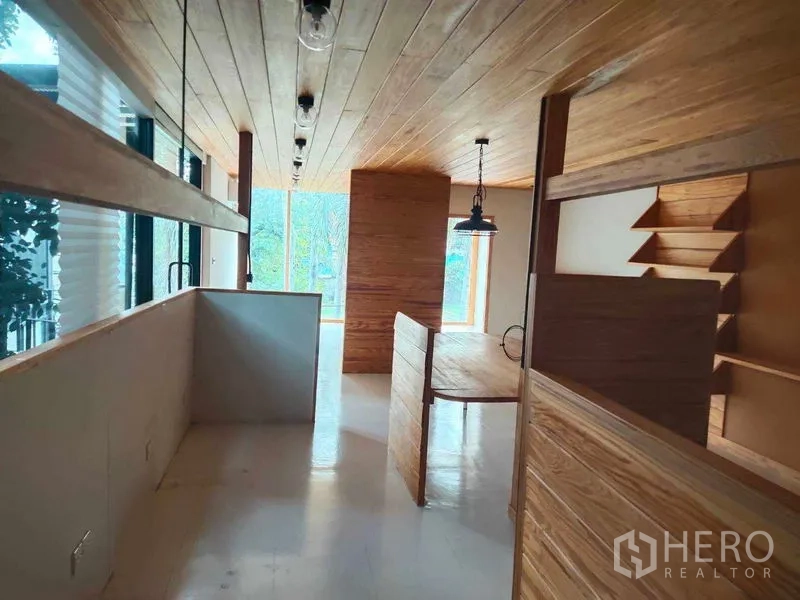 Office Space for rent in Khlong Toei, Bangkok - Open workspace with wood partitions, a long counter, track lighting, and big windows facing greenery.
