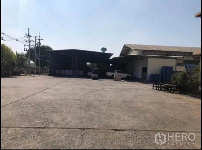 工厂 出租在Bang Khla, Chachoengsao - 两侧厂房之间的大面积水泥前院，附近有电线杆。