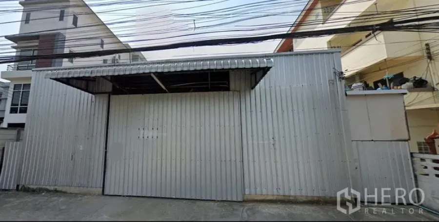Warehouse for rent in Bang Kapi, Bangkok - Front view of the warehouse with closed metal doors facing the street.