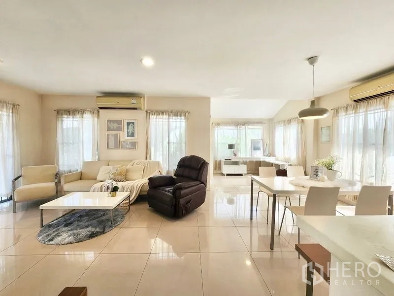 Detached House for rent in Prawet, Bangkok - Spacious living and dining area with glossy tiles, sofas, large windows and air-conditioning units.