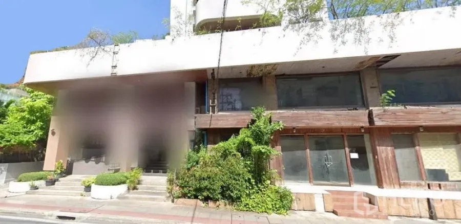 Retail Space for rent in Watthana, Bangkok - Street-facing retail facade with wide steps, large glass windows, double glass doors, wood accents, shaded canopy and greenery along a broad sidewalk.