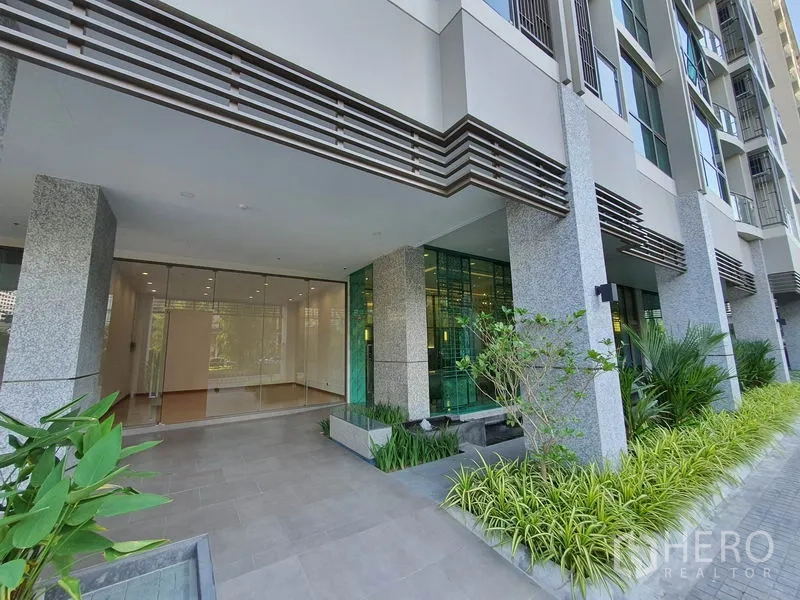 Retail Space for rent in Watthana, Bangkok - Modern building entrance with greenery leading to the retail unit’s glass façade.