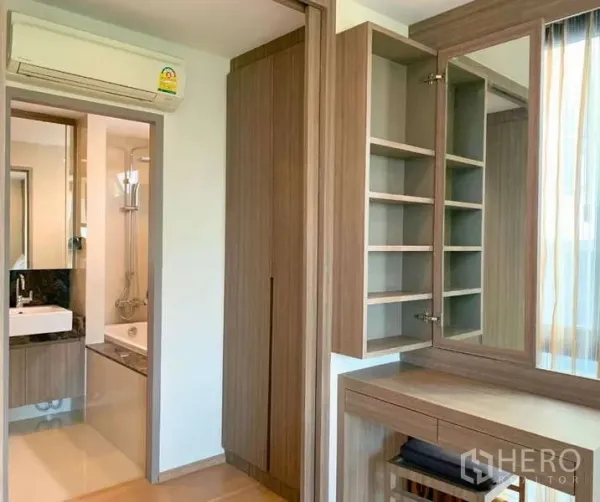 Condominium for rent - Bedroom dressing area with built-in wardrobes, open shelves, and doorway to a bathroom.