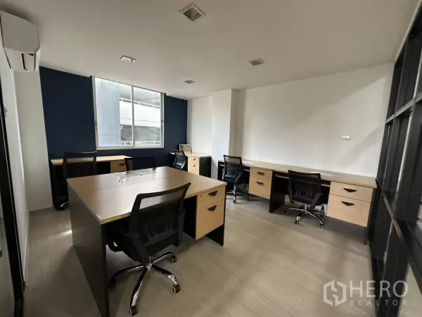 Office Space for rent in Watthana, Bangkok - Private team room with several desks by a window and a navy accent wall.