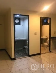 办公空间 出租在Bang Rak, Bangkok - 办公室内卫生间与多功能区入口，瓷砖地面与紧凑洁具。