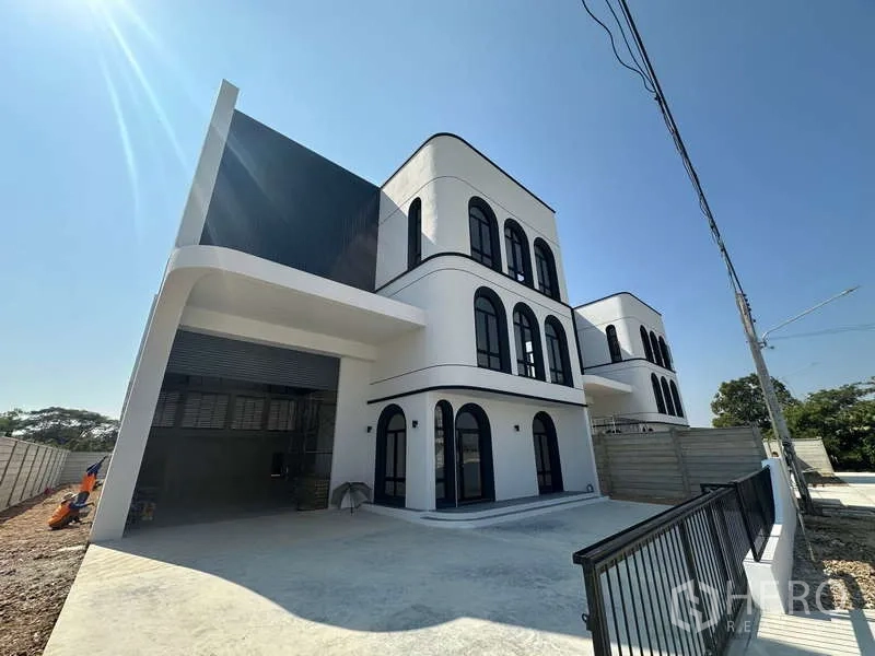 Factory for sale in Lam Luk Ka, Pathum Thani - Contemporary factory facade with covered loading bay, large roller shutter and office block.