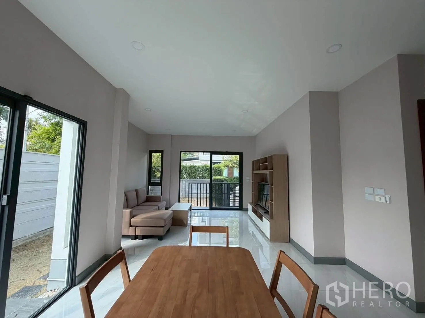 Detached House for rent or sale in Prawet, Bangkok - Open-plan living and dining area with sofa, dining table, TV cabinet, and wide sliding doors.