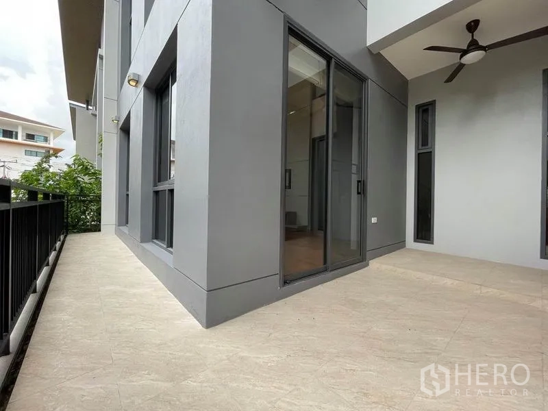 Detached House for rent in Bang Na, Bangkok - Side terrace with sliding glass doors, ceiling fan and metal railing.