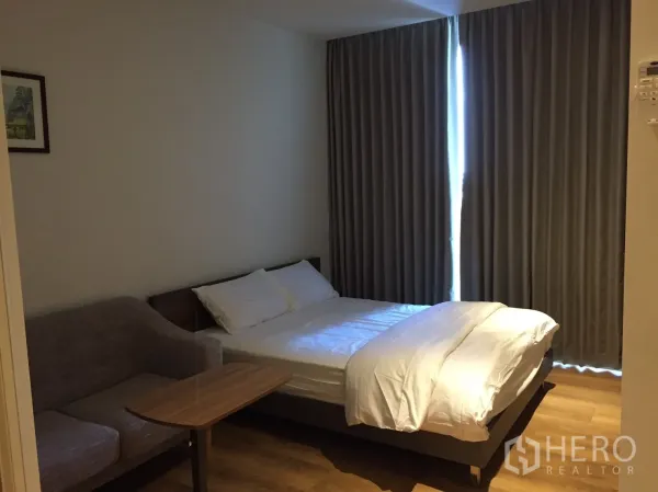 Condominium for rent or sale in Khlong Toei, Bangkok - Bright sleeping area with blackout curtains, bed and compact seating in a Bangkok condo.