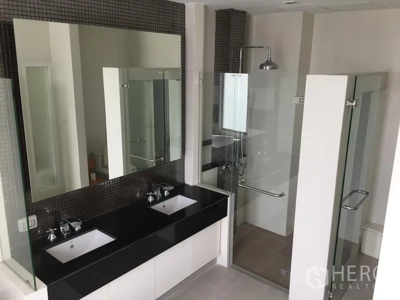 Townhouse for sale in Huai Khwang, Bangkok - Contemporary bathroom featuring a double vanity and a glass-enclosed shower.