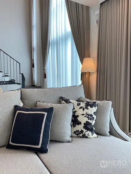 Detached House for rent or sale in Bang Kapi, Bangkok - Close-up of cozy sofa and cushions next to full-height drapes.