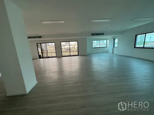 Office Space for rent - Spacious open office with large windows and sliding glass doors to a balcony, wood floors and city views.
