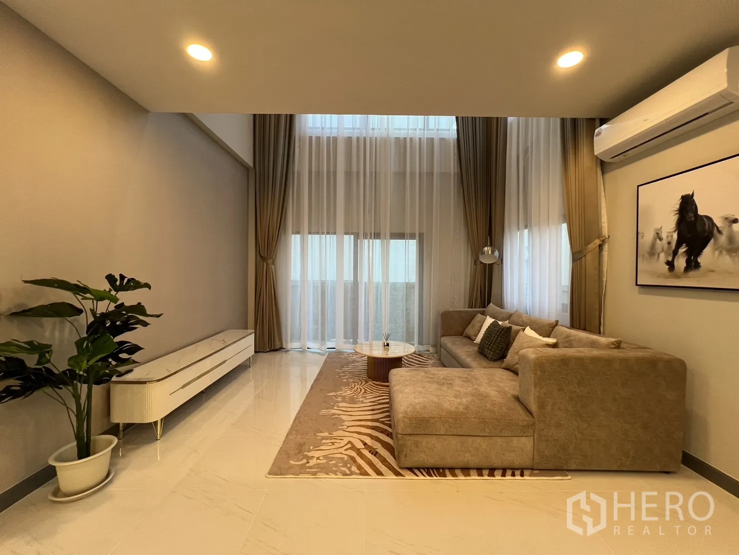Detached House for rent or sale in Bang Phli, Samut Prakan - Cozy living room with sectional sofa, rug and wide draped windows.