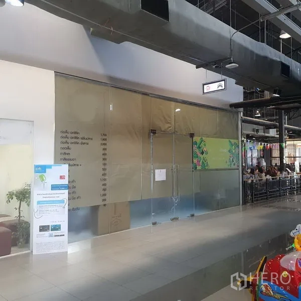 Retail Space for rent in Khlong Toei, Bangkok - Empty 74 sqm retail unit with full-height glass storefront inside a modern mall corridor, polished tile floor and exposed duct ceiling near BTS Phrom Phong.