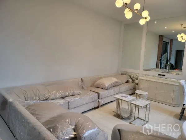 Detached House for rent - Cozy lounge with L-shaped sofa, wall mirror and modern chandelier.